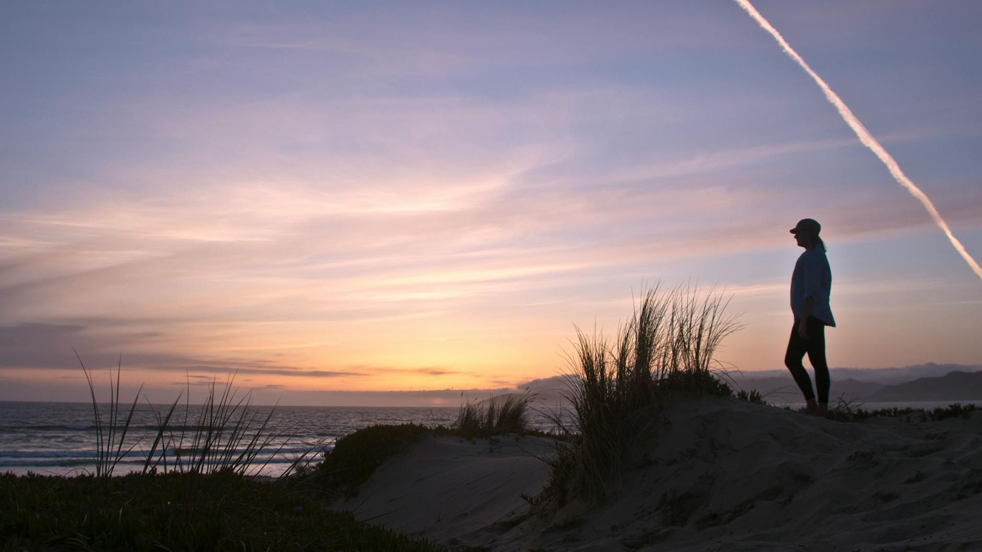 Silhouette of a person walking at sunrise in a calm natural environment.